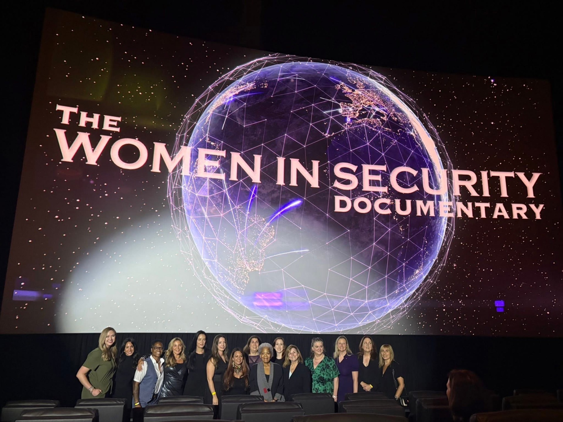 A group gathered on a cinema stage in front of the film's title screen after a screening.